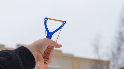 The child aims the slingshot up into the sky.