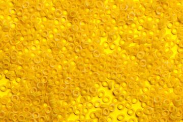 pasta in the form of small circles on a yellow background. panel. texture.