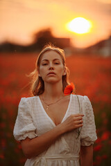Portrait of a woman on a background of sunset and red flowers