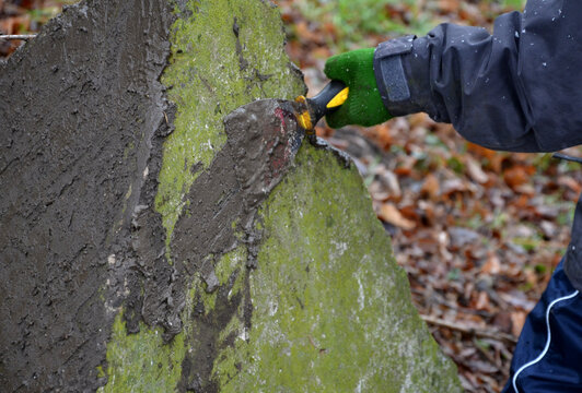 Little boys playing on throwing walls with mud cement plaster. they borrowed tools from dad. spatulas smear mud like tile adhesive. military roadblock concrete pyramid, in forest