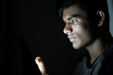 young man sitting on bed using smart phone at night 