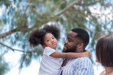 Happy African American father hug African American daughter girl on the beach, thaliand