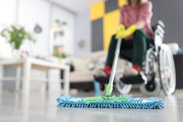 Woman in wheelchair washes floor with mop