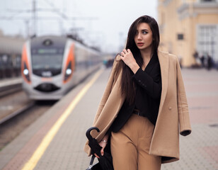 Fototapeta premium Woman model stands at train station in suit