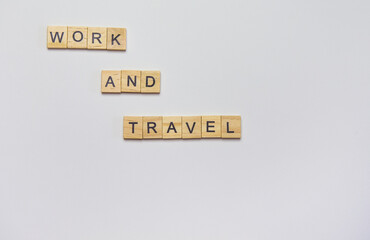 Wooden inscription from cubes - work and travel on a white background, top view.