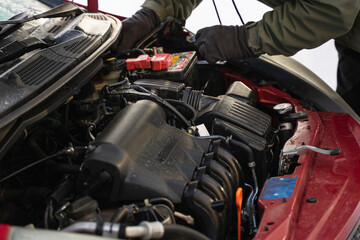 Fototapeta na wymiar Worker's hands repair car, install new battery