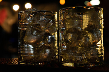 Two bar glasses full of ice for cocktails, close-up , in a low key
