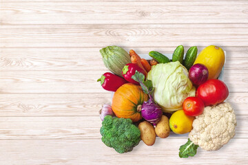 Fresh vegetables in a box, top view on a light wooden background. Place for inscription