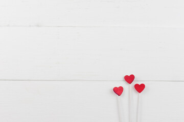 Three small red hearts on white sticks in the lower right corner on a white background.