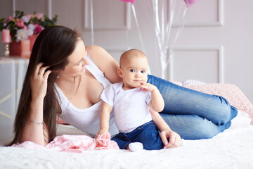 Happy family. Mother with her little baby in light interior livihg room. Mother's day celebration with gifts and flowers