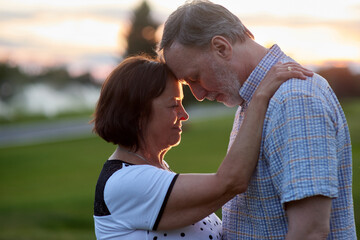 Loving mature couple with closed eyes. Close-up middle-aged man and woman outdoors.