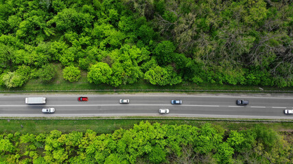 Aerial. Traffic on the intercity highway between the natural parkland. Top view from drone.