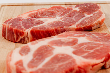 fresh raw marbled pork steak on a solid beech wood cutting board