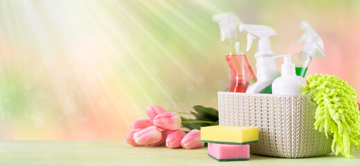 Spring cleaning concept - cleaning supplies and flowers on blur background, copy space