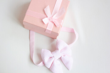 Baby's bootees with pink bow and gift box on light background