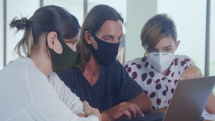 Colleagues team with face mask discuss online project use laptop at workplace, coworkers talk work together share ideas on digital marketing strategy at office meeting during coronavirus epidemic - Powered by Adobe