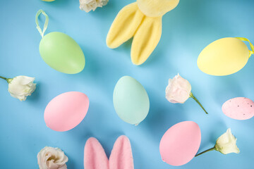 Spring Easter holiday greeting card, sale, invitation background. Colorful Easter Eggs and Bunny Rabbits, with Spring flowers on blue background top view flatlay with copy space for text