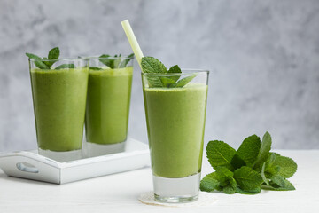 Freshly blended green fruit smoothie in glass.