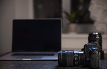 Fototapeta na wymiar Digital professional camera on the table near the laptop.