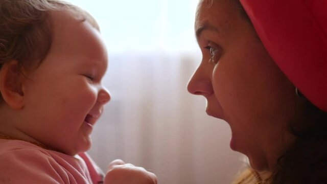 Mom dabbles with her daughter, puffs her cheeks, builds faces. HD, 1920x1080, slow motion.