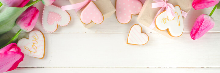 Valentine Day concept, Spring Woman Day Holiday, Mothers Day background, Red tulip flowers bouquet, craft paper gift box, heart shaped traditional sugar cookies, White wooden background copy space