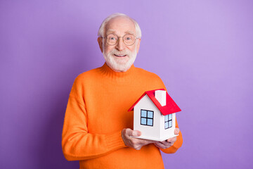 Photo of positive aged man hands hold little house beaming smile isolated on violet color background