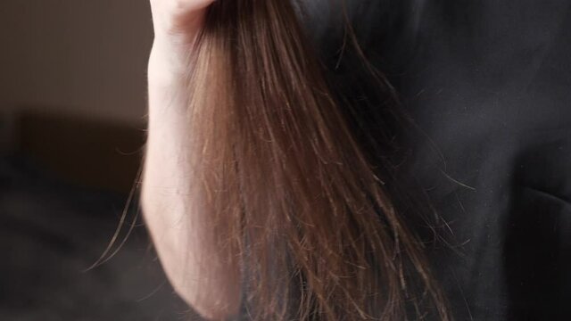 Skilled woman hands comb split and overdried long dark brown hair tips gently holding special black brush extreme close view slow motion