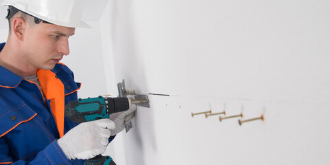 furniture assembly worker, fixes the suspension system with self-tapping screws and a screwdriver