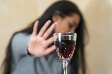 Giving up alcohol. A young woman at the table refuses a glass of red wine with her hand