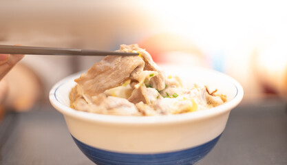 Hand uses chopsticks to pick up tasty japanese ramen noodles with vegetarian and smoke in bowl on the wooden table
