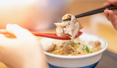 Hand uses chopsticks and spoon to pick up tasty japanese ramen noodles with vegetarian and smoke in bowl on the wooden table