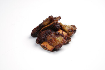 Small pieces of fried ribs that are dark brown in color. The beef ribs have been seasoned, then sprinkled with typical Indonesian spices. Spicy fried ribs. Fried ribs isolated on white background.