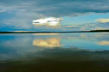 A calm evening sky landscape of pastel colors with a reflection in the smooth waves of a large lake. Natural background