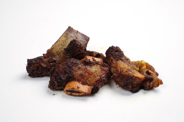 Small pieces of fried ribs that are dark brown in color. The beef ribs have been seasoned, then sprinkled with typical Indonesian spices. Spicy fried ribs. Fried ribs isolated on white background.
