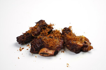 Small pieces of fried ribs that are dark brown in color. The beef ribs have been seasoned, then sprinkled with typical Indonesian spices. Spicy fried ribs. Fried ribs isolated on white background.