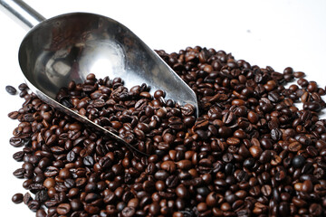 Scoop out ripe coffee beans using a large spoon made of wood and iron. Coffee beans scattered on the floor. Details texture of dark brown coffee beans. Graphic resourches for design template.