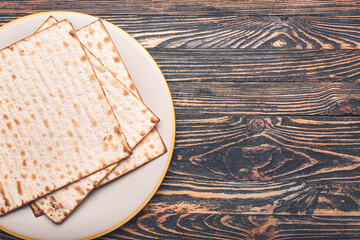Plate with Jewish flatbread matza for Passover on wooden background