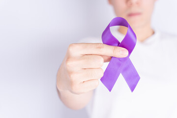 World cancer day, hands holding purple ribbon on grey background with copy space for text....