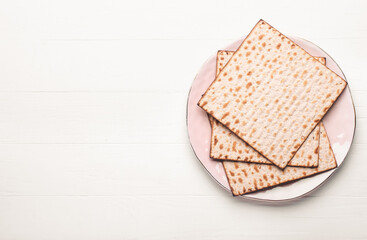 Plate with Jewish flatbread matza for Passover on white wooden background