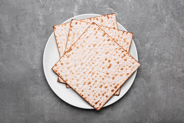 Plate with Jewish flatbread matza for Passover on grey background