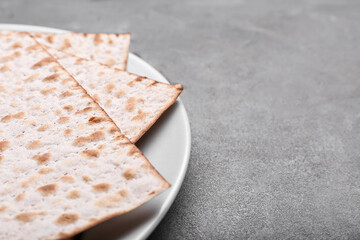 Plate with Jewish flatbread matza for Passover on grey background, closeup