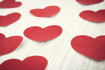 red paper hearts on light wooden background.