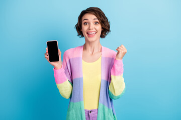 Photo portrait of cheerful girl celebrating holding phone with blank space in one hand isolated on pastel blue colored background