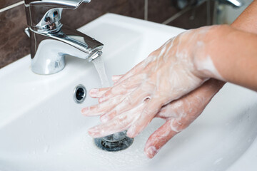 Hygiene concept. Washing hands with soap under the faucet with water