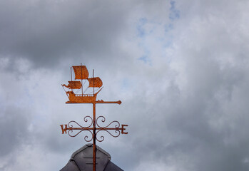 Ship galleon weather vane against stormy grey sky.