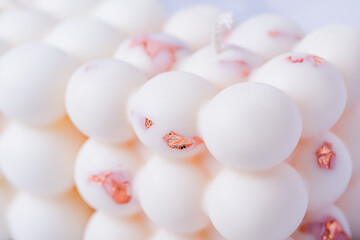 Close-up of white bubble cube candles with copper metal flakes, abstract background