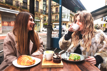Two friends having breakfast at a terrace on a winter morning in Donostia-San Sebastian; Basque...