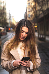 Young caucasian brunette woman using a smartphone at the street