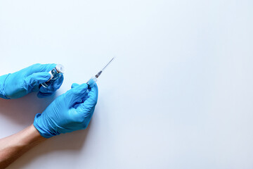 Medical syringe and ampoule with medicine in the hands of a doctor in medical gloves on a white background.