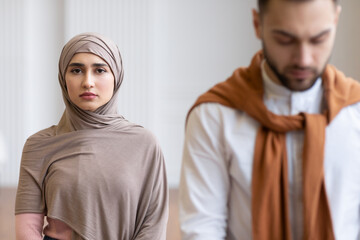 Muslim Wife In Hijab Standing Behind Husband Indoors